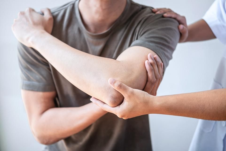 A man is getting his elbow examined by a nurse.