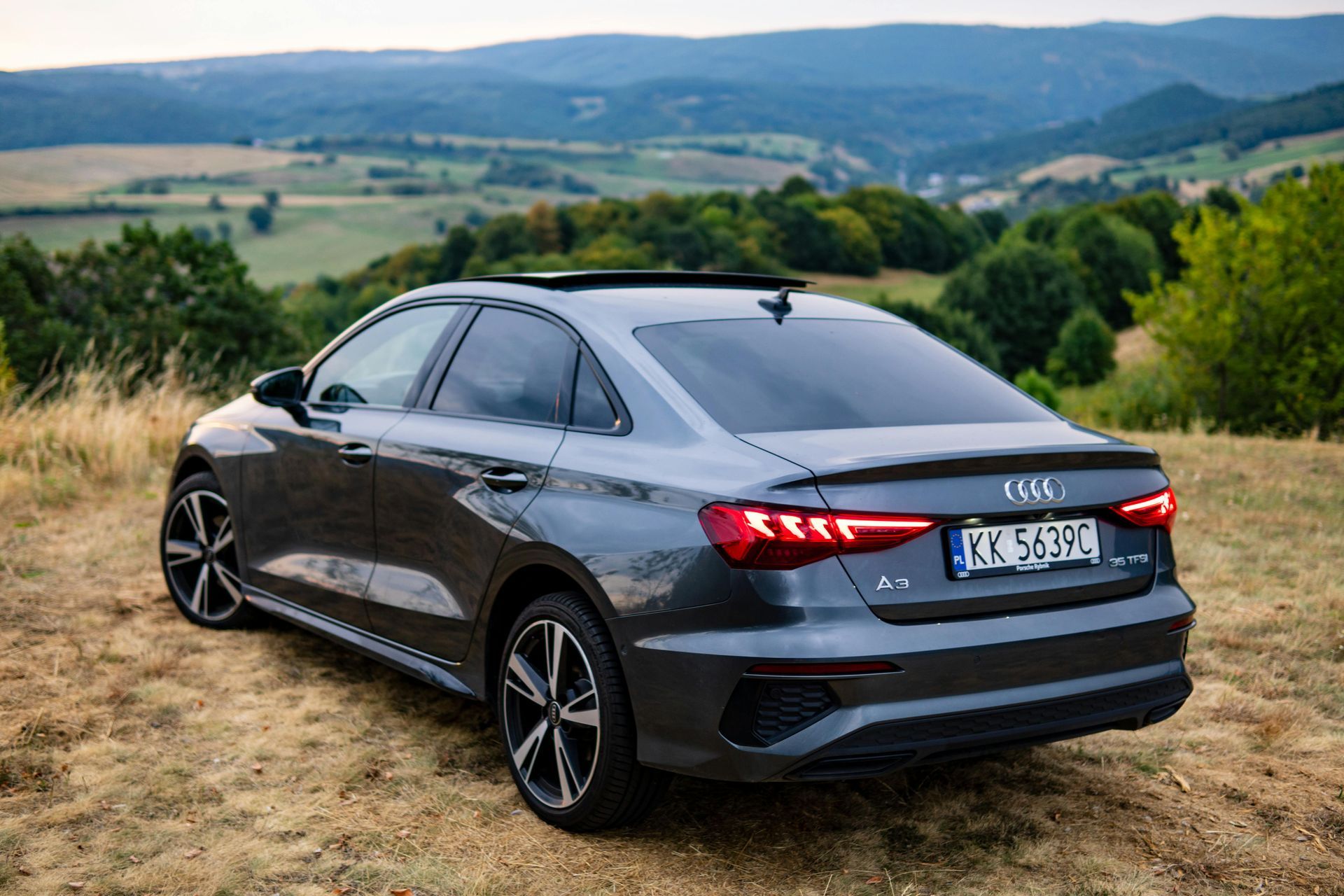 A gray audi a3 sedan is parked on top of a hill.