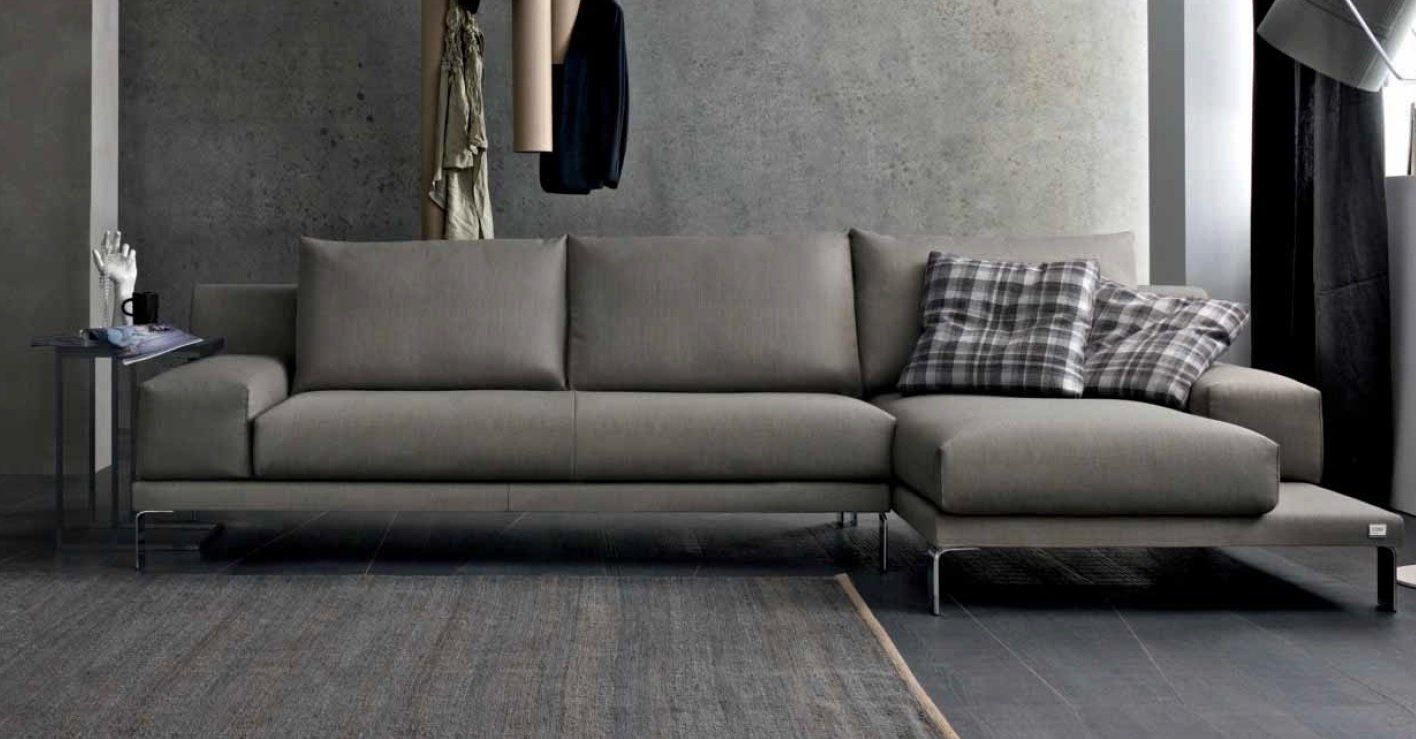 Divano componibile grigio moderno in un soggiorno minimalista con cuscini decorativi.