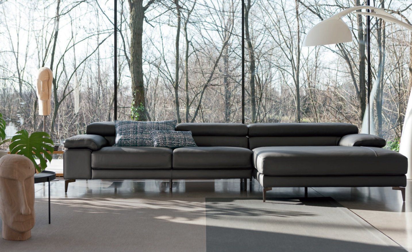Divano componibile grigio in un soggiorno moderno con ampie finestre e luce.