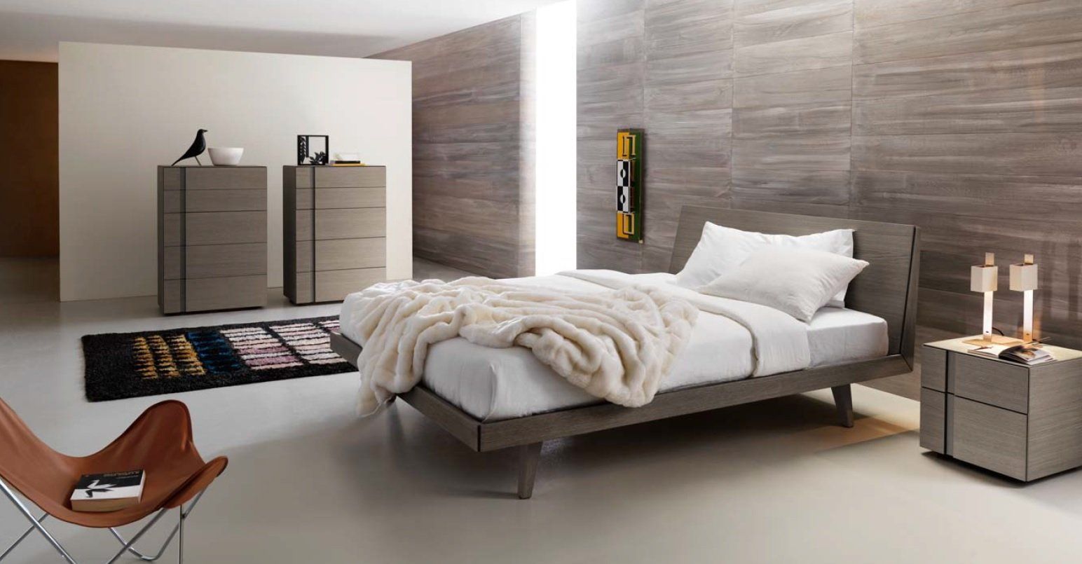 Camera da letto moderna con letto, cassettiera, comodino e poltrona a farfalla; toni del grigio e del beige.