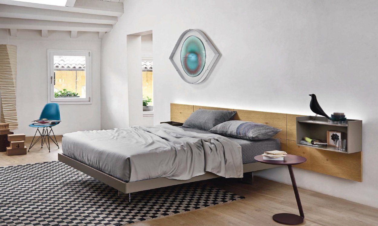 Camera da letto moderna con letto sospeso, testiera in legno, biancheria grigia, opere d'arte.