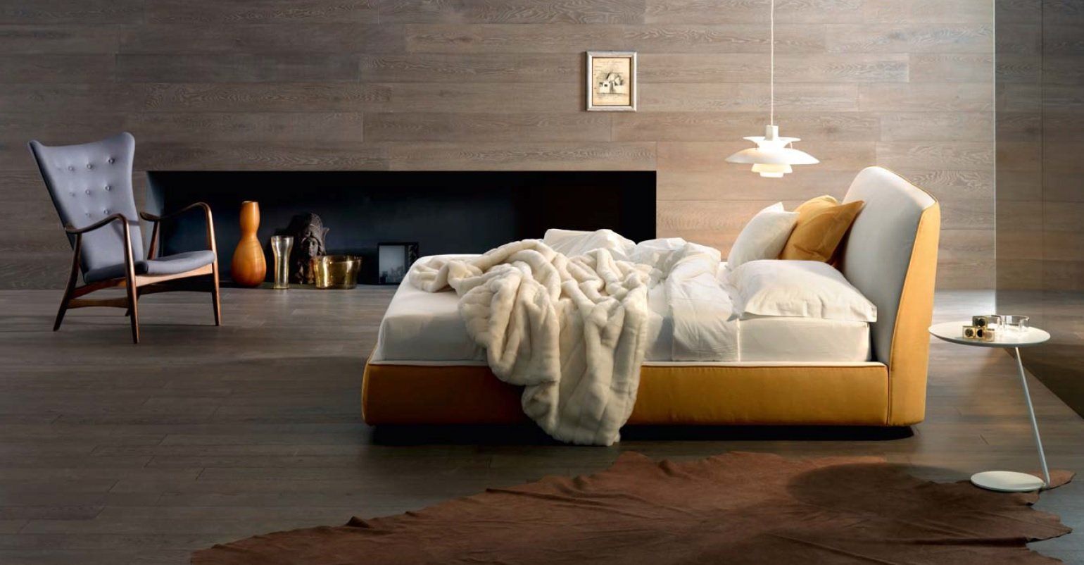 Camera da letto con letto giallo, sedia grigia, tappeto marrone e camino decorativo.