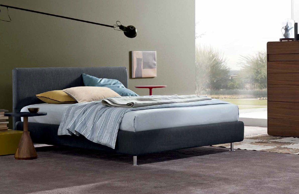 Letto grigio in una camera da letto moderna con coperte e cuscini morbidi.