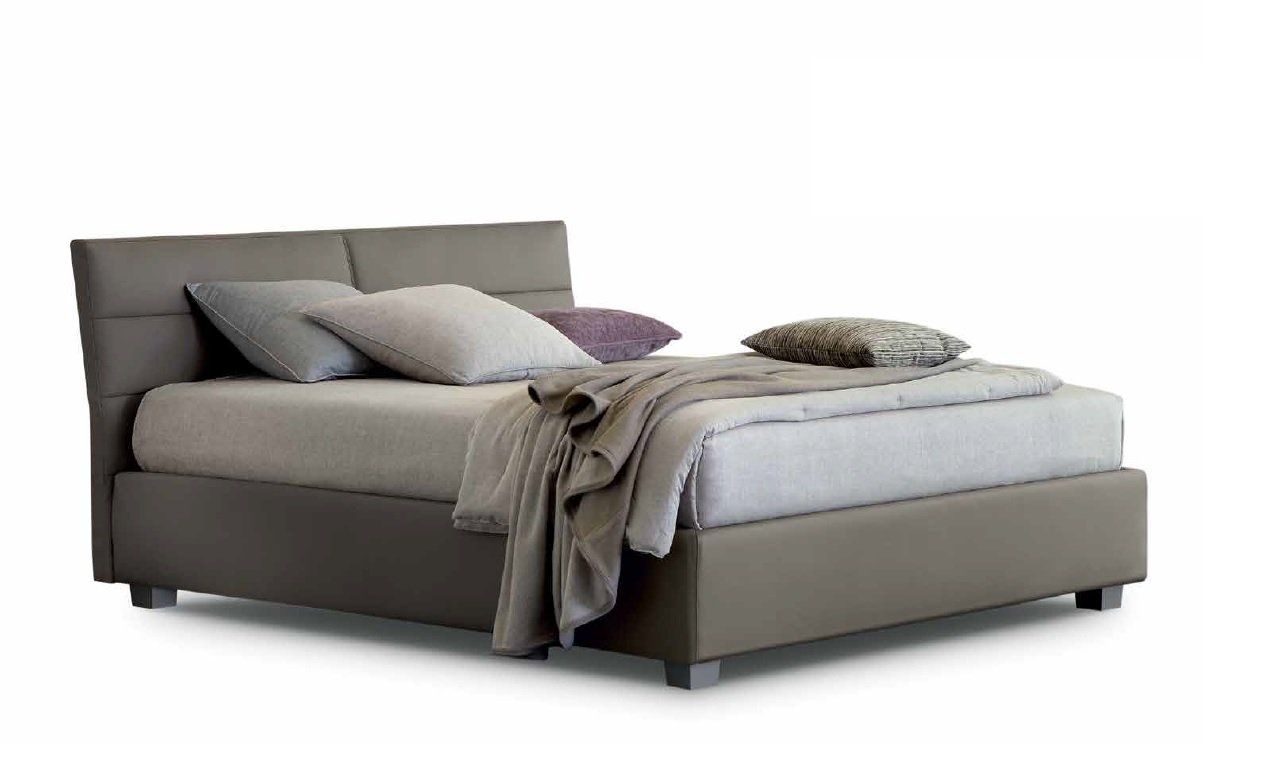 Letto imbottito grigio con cuscini e coperta.