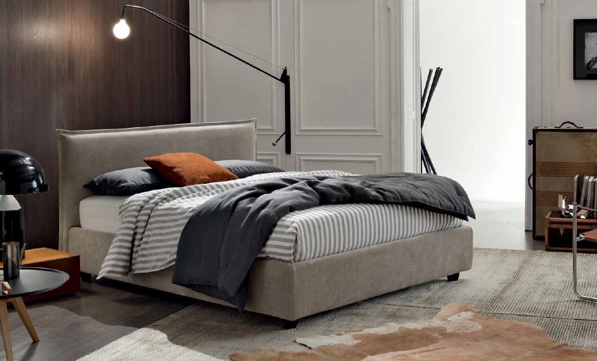 Camera da letto con letto, cuscini e coperta. Arredamento moderno con pannelli in legno e tappeto.