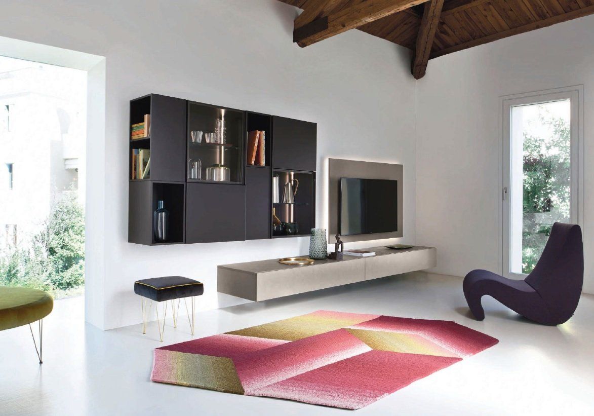 Soggiorno moderno con mensole sospese, TV, tappeto a fantasia e sedia viola.