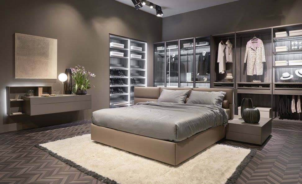 Camera da letto moderna con letto, cabina armadio e toletta in tonalità neutre, tappeto e illuminazione d'accento.