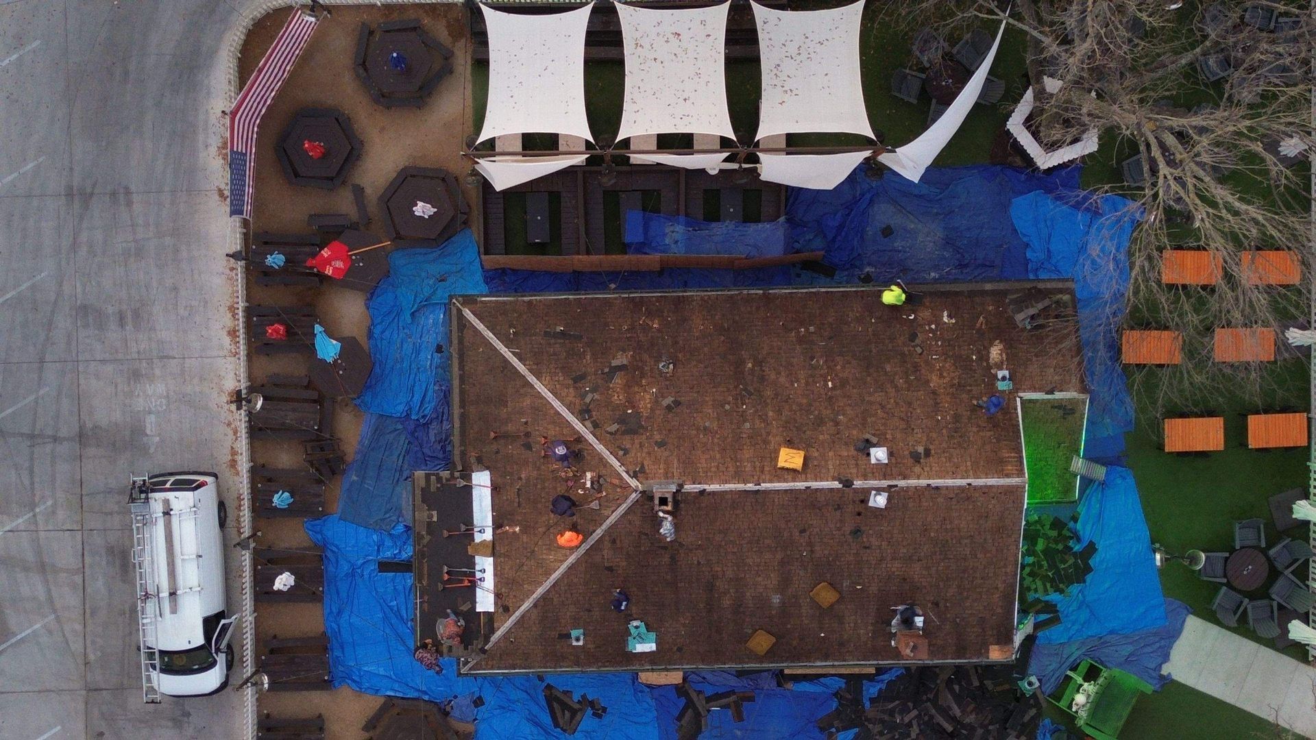 An aerial view of a building with a blue tarp on the roof