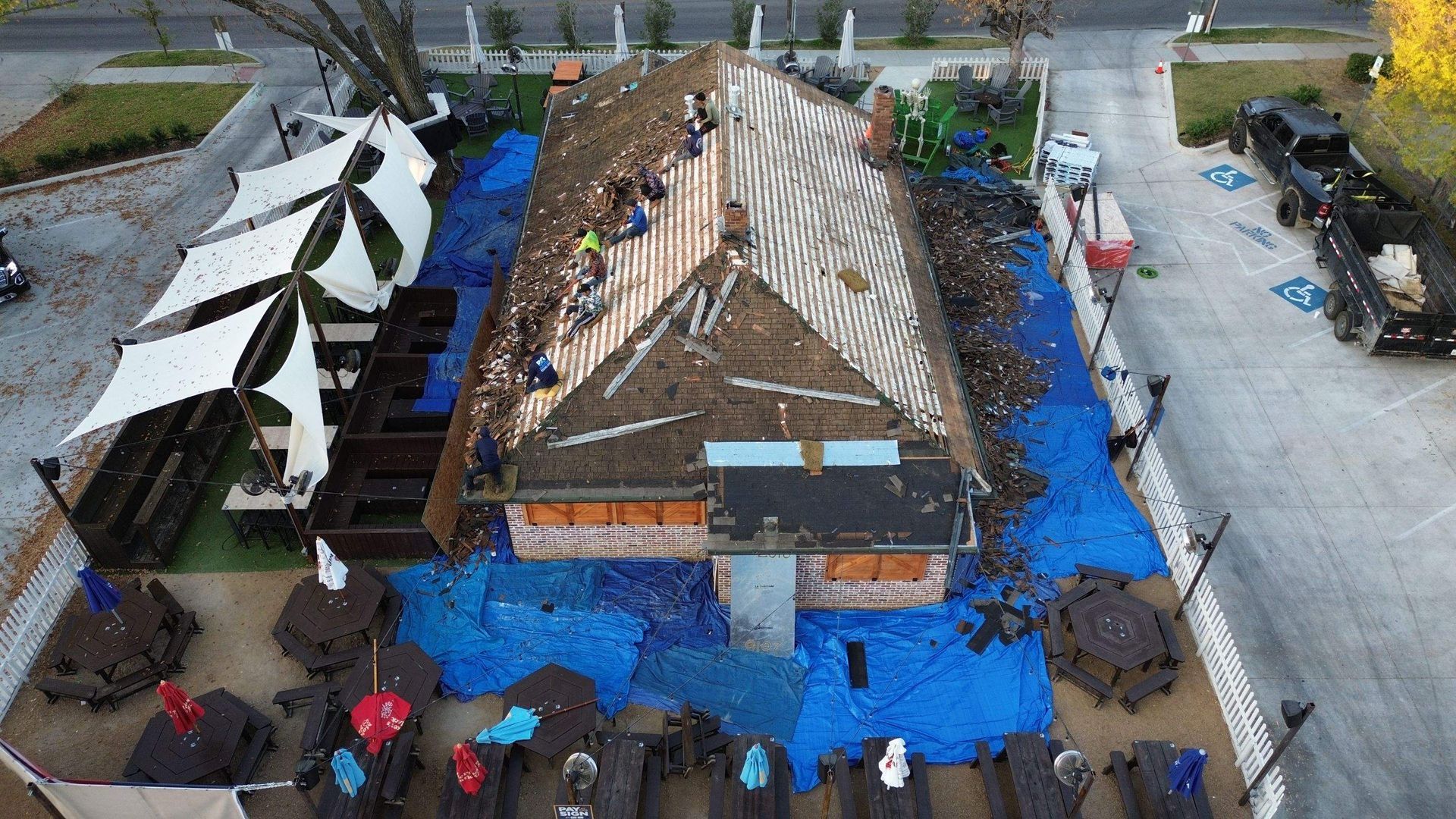 An aerial view of a building under construction with tables and chairs covered in blue tarps.