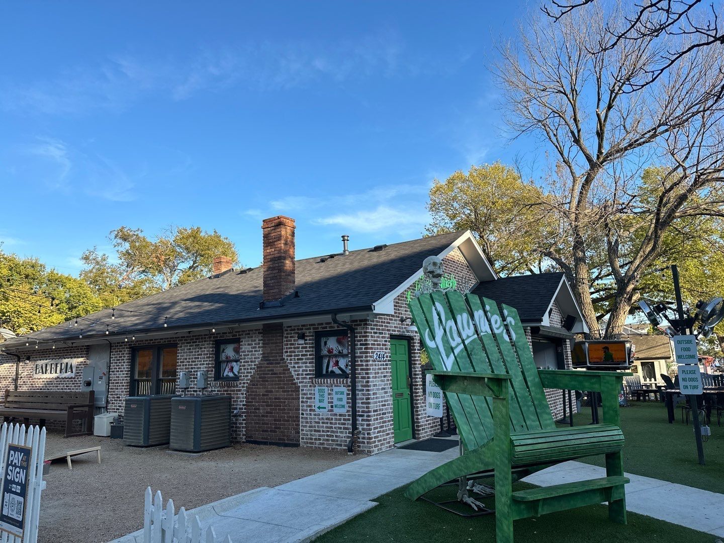 A large green chair is sitting in front of a brick building.