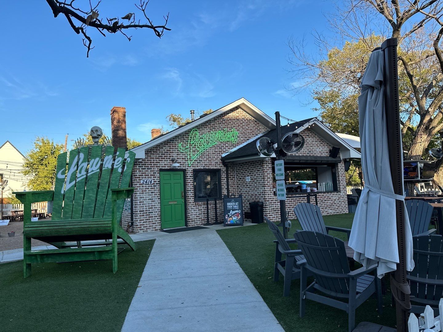 A large green wooden chair is sitting in front of a building.