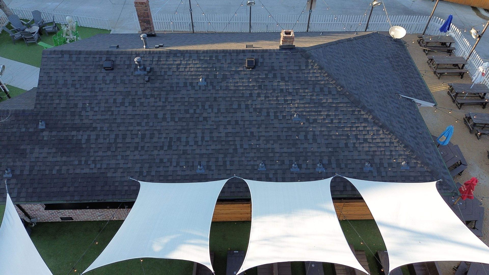 An aerial view of a roof with a few white tents in front of it