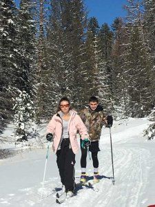 A man and a woman are cross country skiing in the snow.