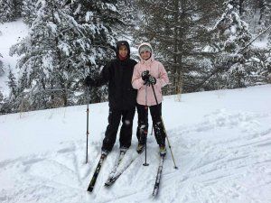 A man and a woman are standing next to each other on skis in the snow.