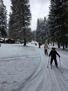 A group of people are skiing down a snow covered road.