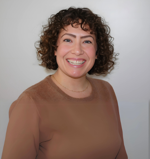 A woman in a scrub top is smiling for the camera.