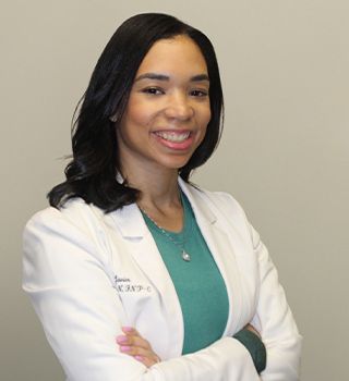 A woman in a lab coat is smiling with her arms crossed.