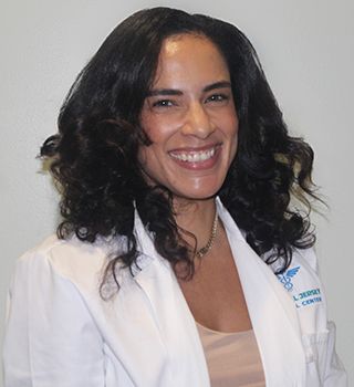 A woman in a white lab coat is smiling for the camera