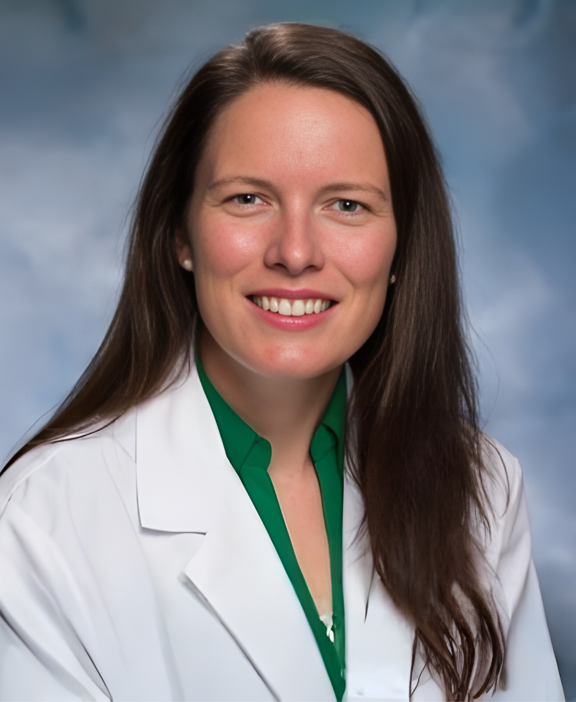 A woman in a blue scrub top is smiling for the camera.