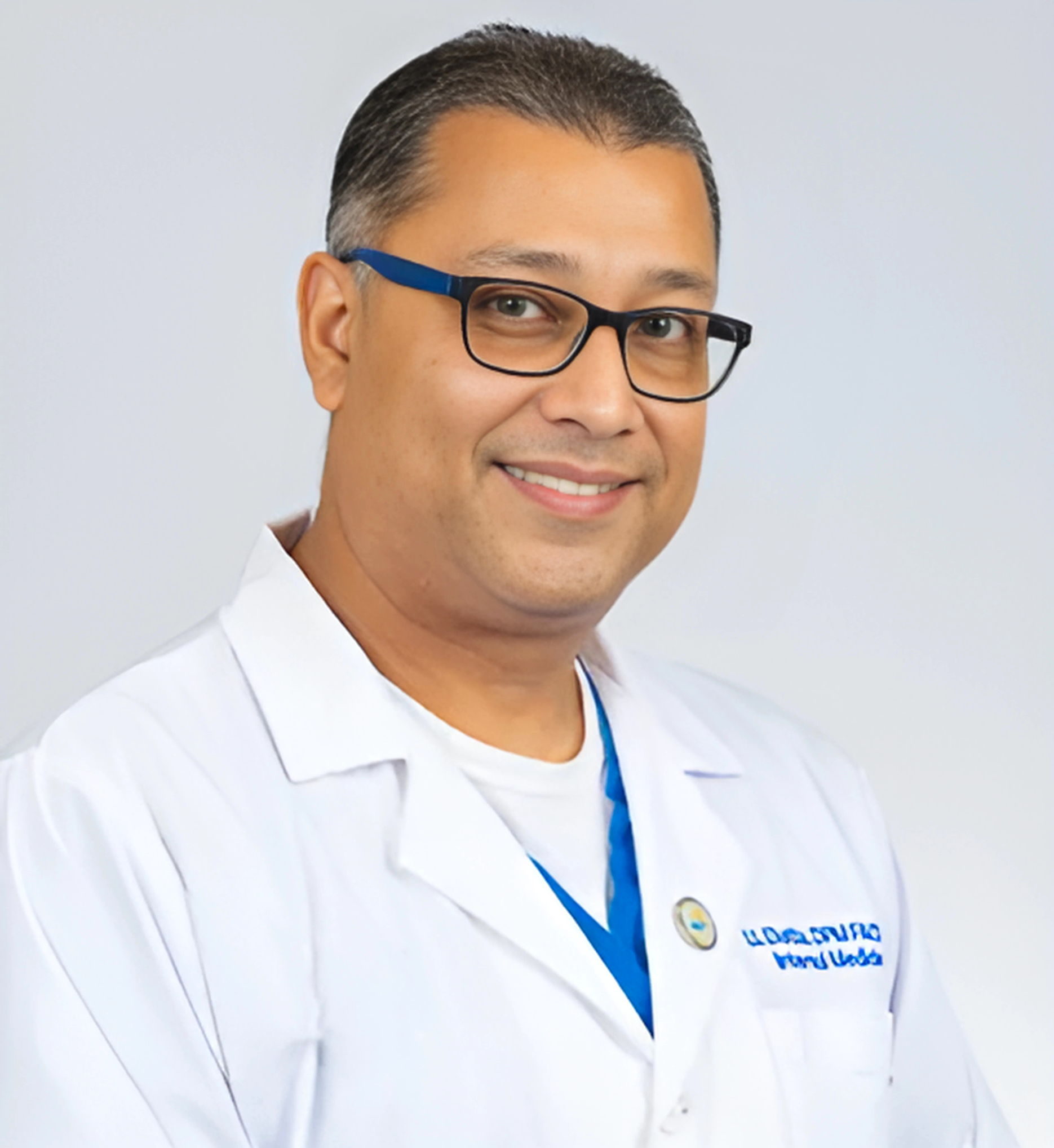 A man wearing glasses and a white lab coat is smiling for the camera.