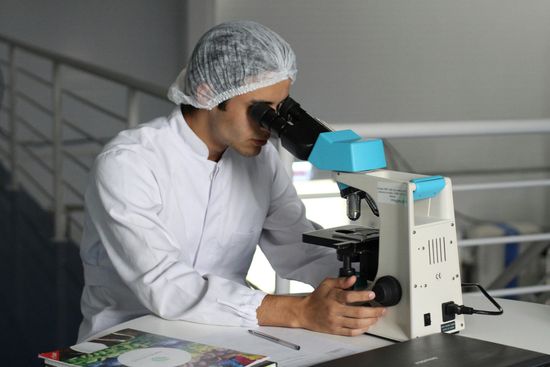 A man is looking through a microscope in a lab.