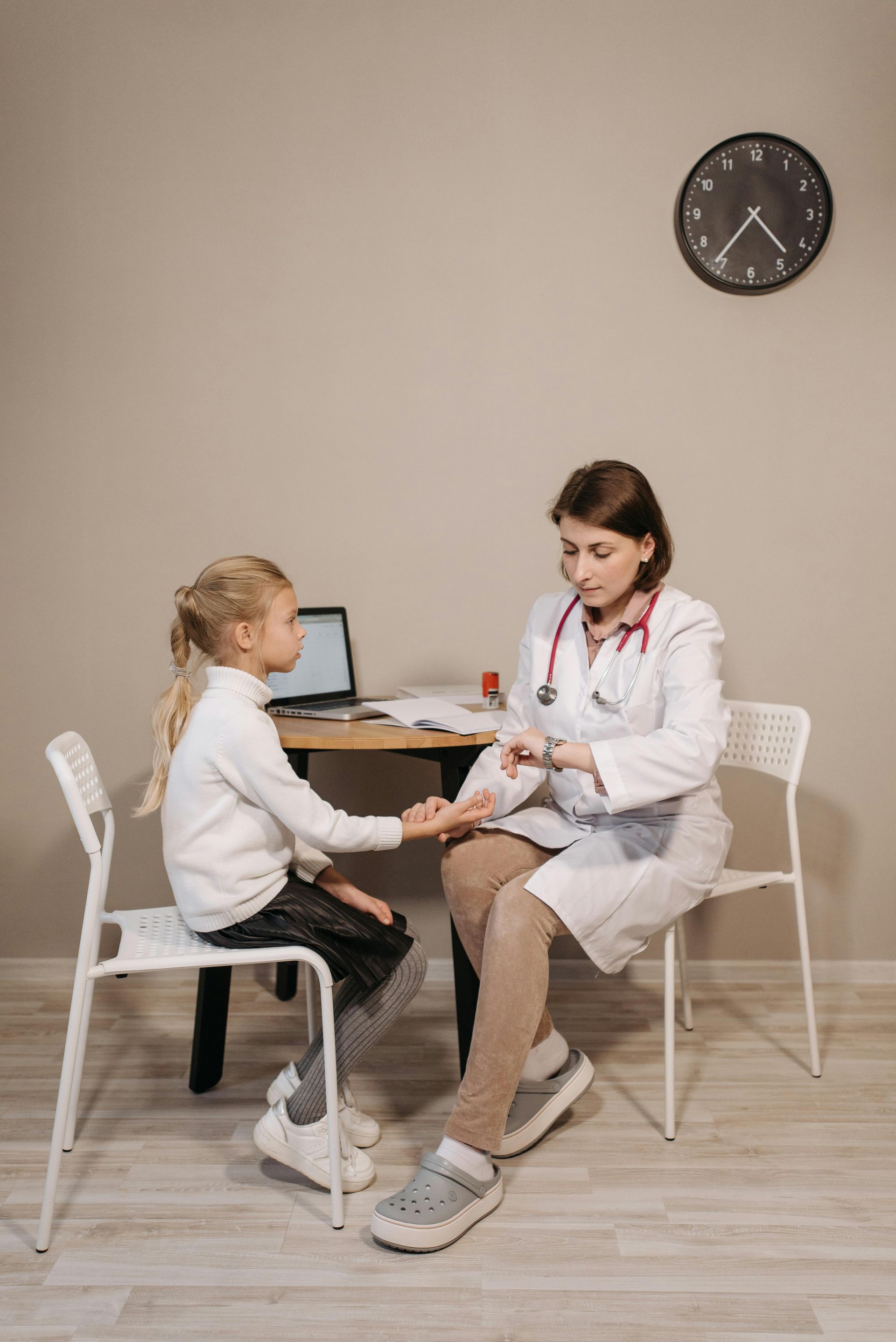 A doctor is sitting at a table talking to a little girl.