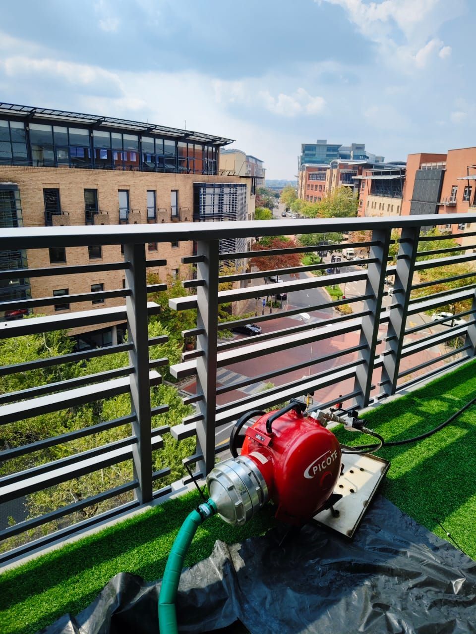 A red machine with a hose attached to it is on a balcony overlooking a city