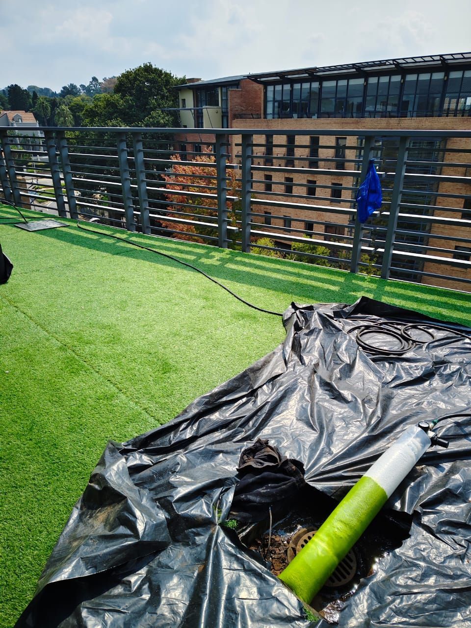 A person is digging a hole in the grass on a balcony.