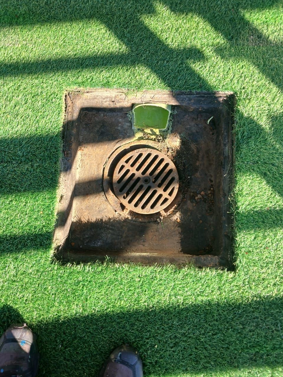 A manhole cover is sitting on top of a green lawn.