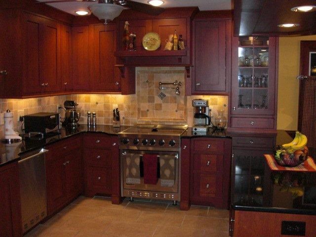 A kitchen with red cabinets and a stove top oven