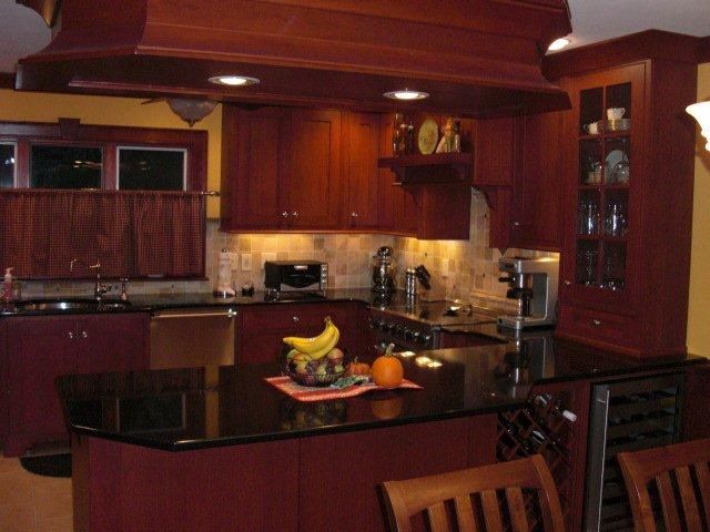 A kitchen with red cabinets and a black counter top