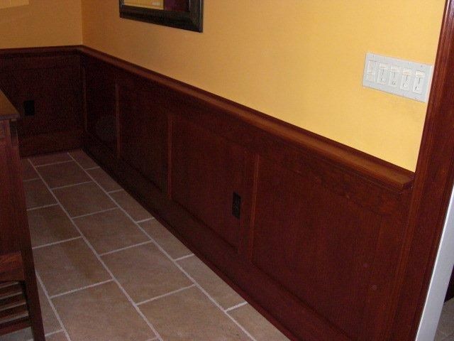 A hallway with wood paneling and a tiled floor