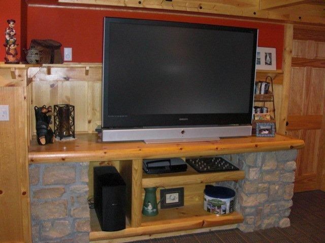 A large flat screen tv is mounted on a wooden entertainment center