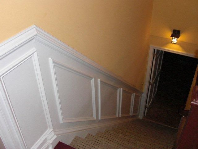 A hallway with stairs leading up to a door