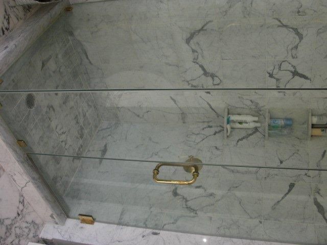 A bathroom with marble walls and a glass shower door