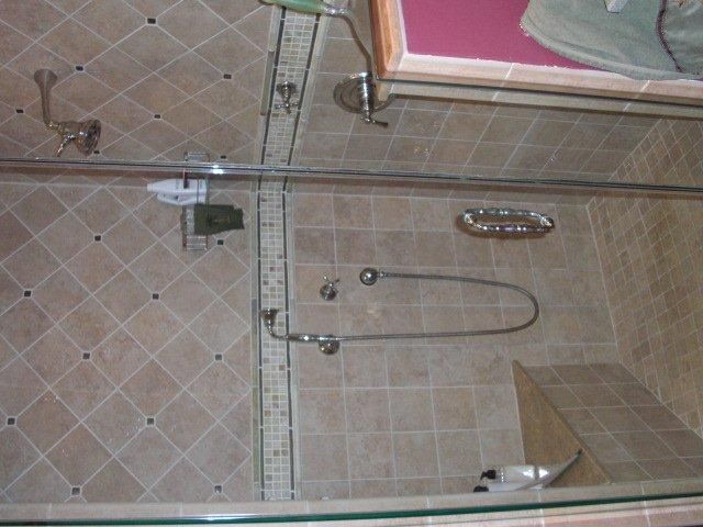 A bathroom with a walk in shower with a glass door