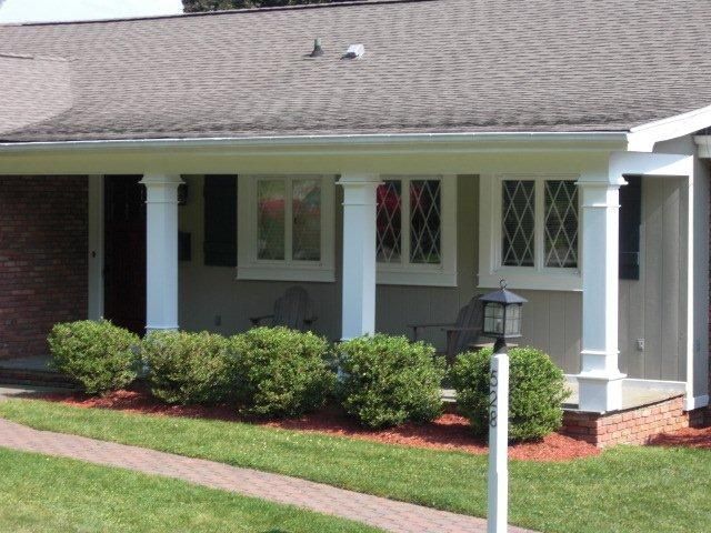 A house with a porch and bushes in front of it
