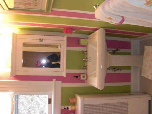 A bathroom with pink and green stripes on the walls