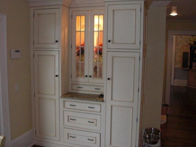 A white cabinet with drawers and a glass door