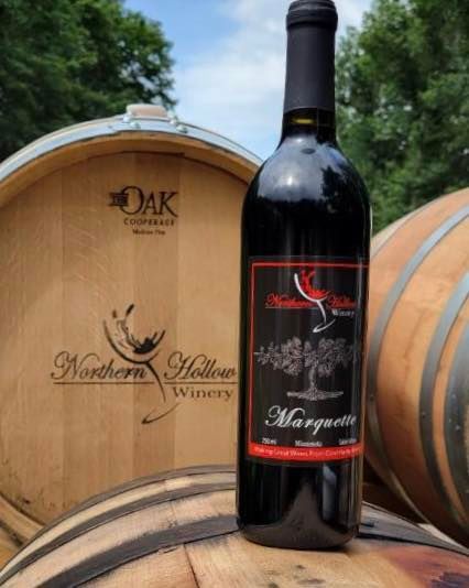 A bottle of margarita wine is sitting on a wooden barrel