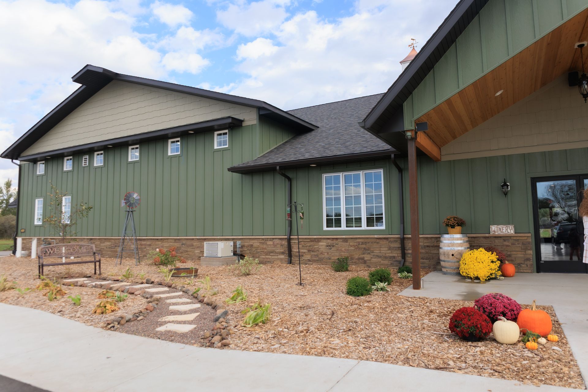 Green building with stone accents, a welcoming entrance, and fall decorations.