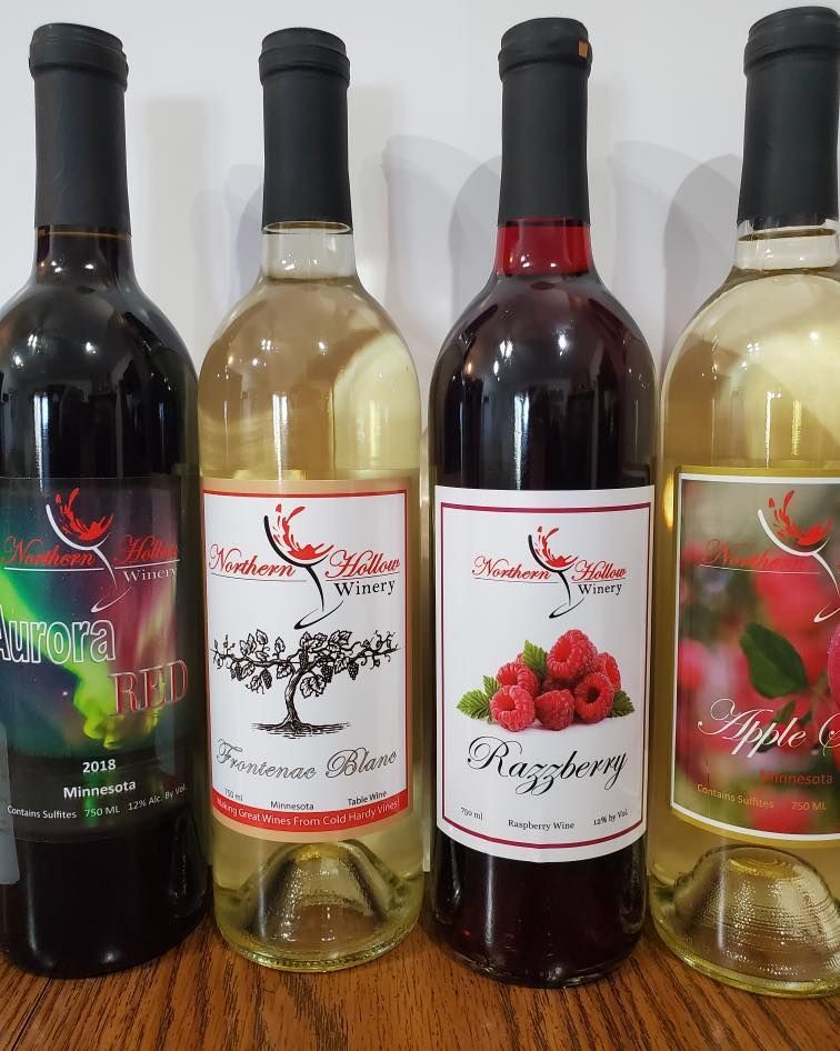 Four bottles of wine are lined up on a wooden table