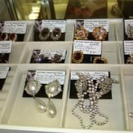 A display case filled with assorted vintage-style costume jewelry earrings arranged on cards in a white partitioned tray.