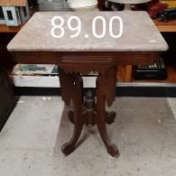A vintage-style wooden side table with a marble top, shown in a retail setting with an 