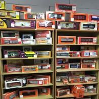 Shelves filled with numerous model train cars in their original rectangular boxes, arranged in a retail store setting.