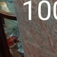 A glass display case containing ornaments, partially obscured by a textured, pinkish-brown surface with the number 100.