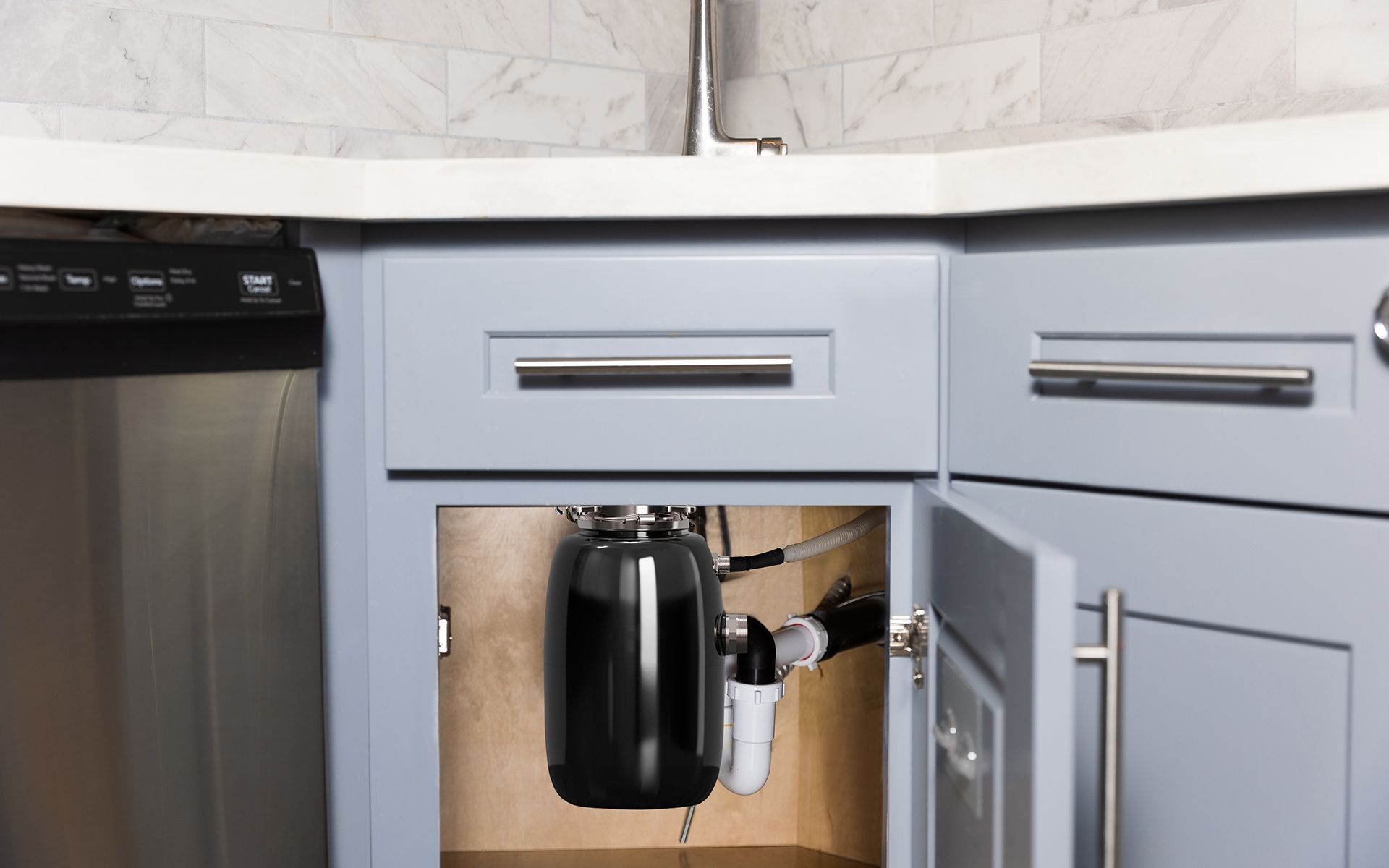 Open kitchen cabinet with a black water filtration system installed.