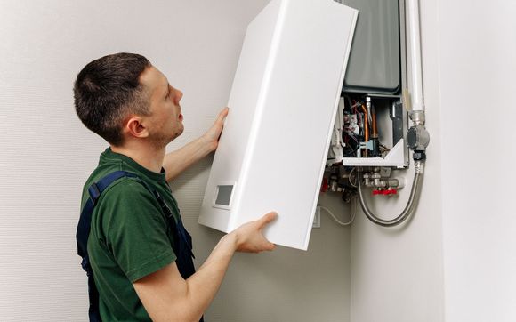 Man installing a white boiler cover on a wall.