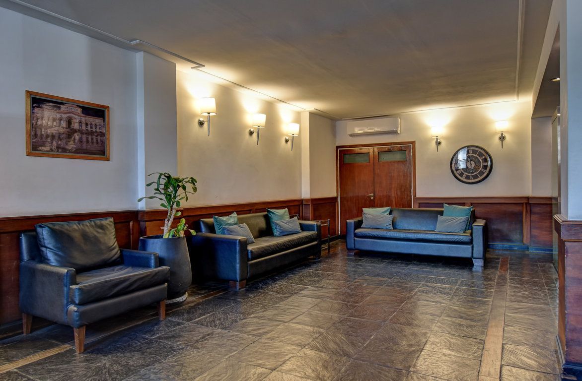 Un vestíbulo con un sofá, sillas y un cuadro en la pared.